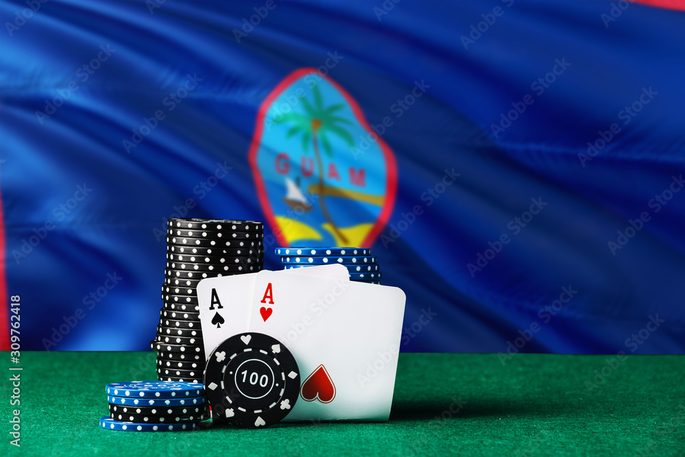 Guam casino theme. Two ace in poker game, cards and black chips on green table with national flag background. Gambling and betting.