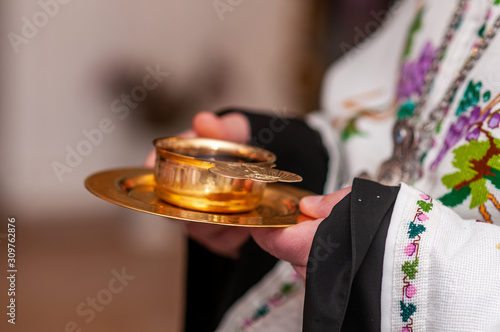 Priest holding gold cup with wine in the hands