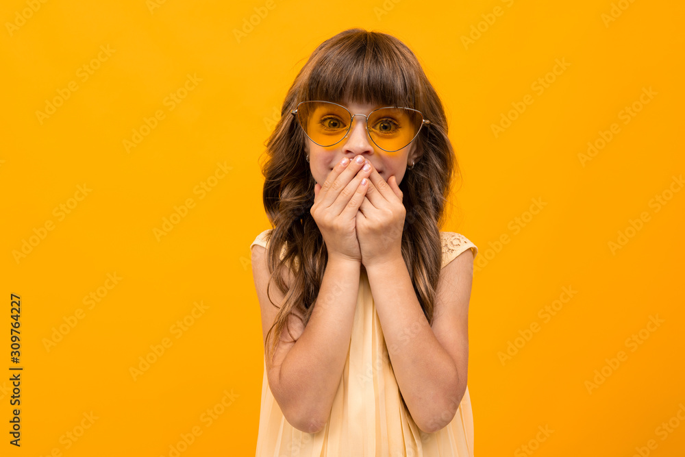 caucasian girl in glasses closed her mouth on a yellow background caucasian girl in glasses closed her mouth on a yellow background