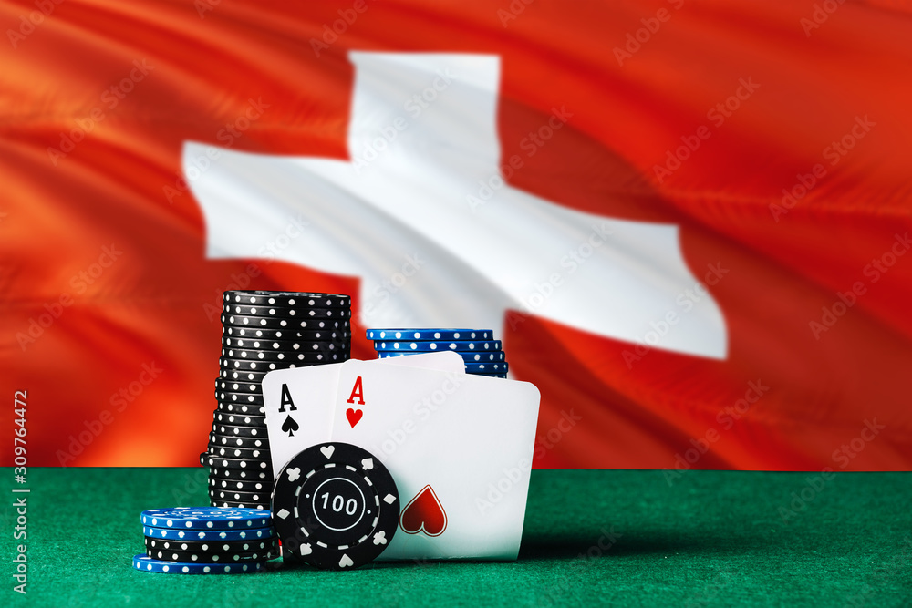 Switzerland casino theme. Two ace in poker game, cards and black chips on green table with national flag background. Gambling and betting.