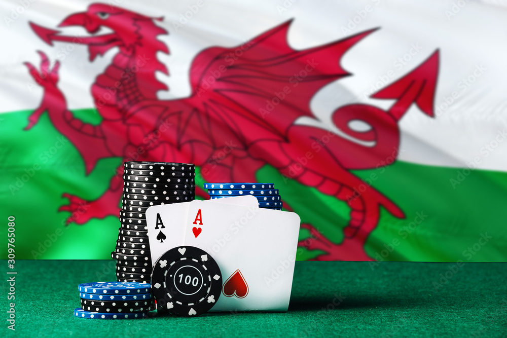 Wales casino theme. Two ace in poker game, cards and black chips on green table with national flag background. Gambling and betting.