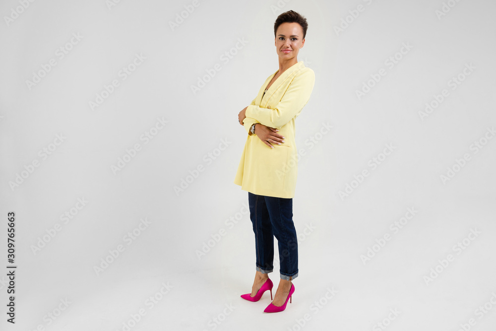 cute brunette with a short haircut in a cream-colored jacket and pink pumps shoes on a gray background cute brunette with a short haircut in a cream-colored jacket and pink pumps shoes on a gray background