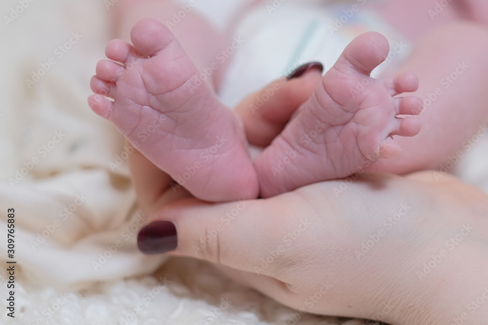 The mother's hand holds the legs of the newborn baby. Skincare. The mother's hand holds the legs of the newborn baby. Skincare.