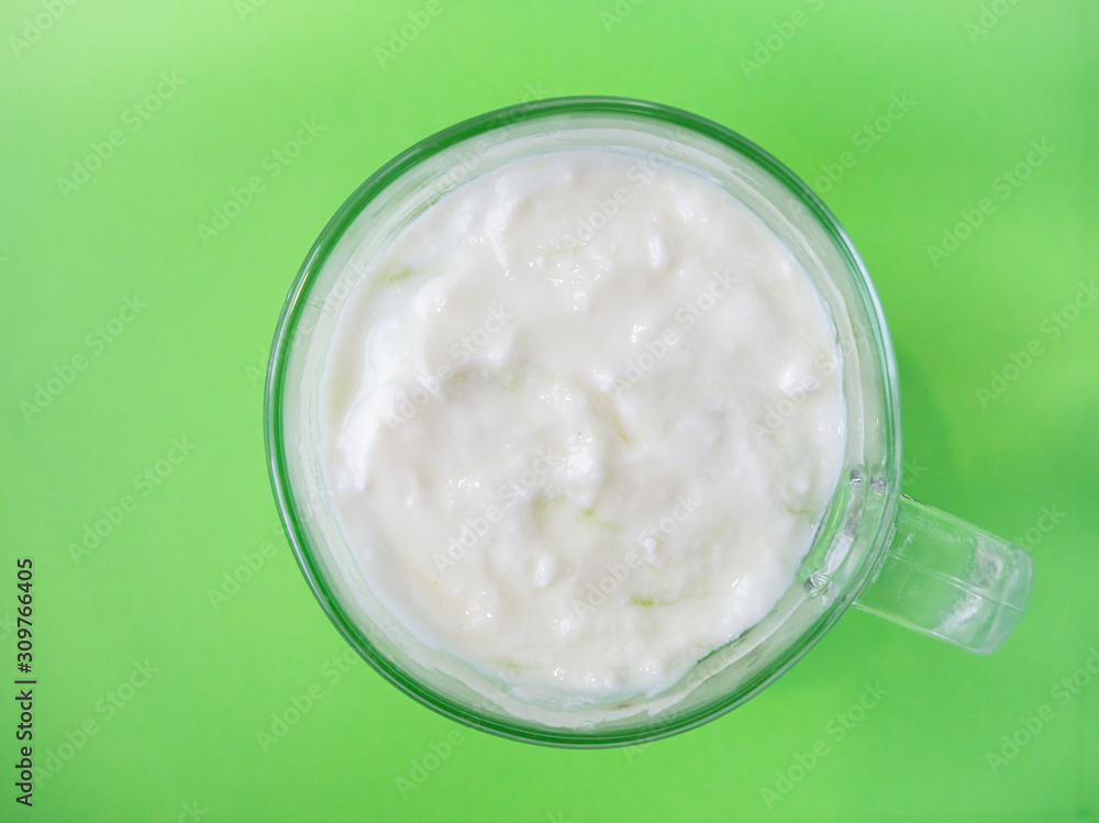 Homemade yogurt in a cup on green background, top view Homemade yogurt in a cup on green background, top view