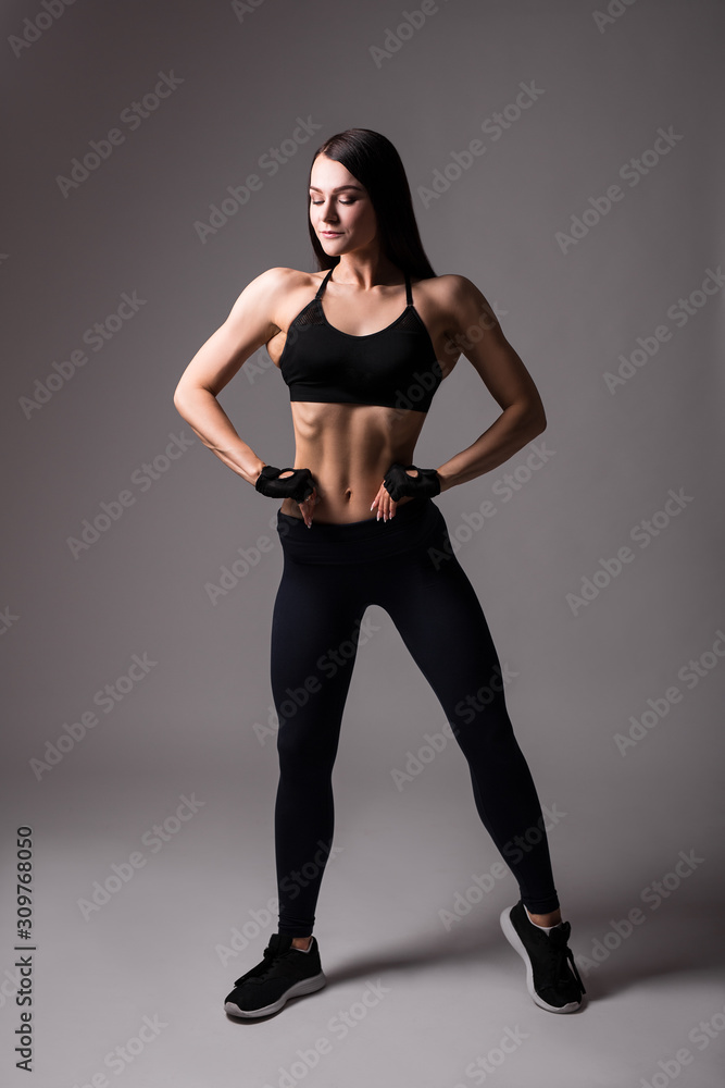 young beautiful sporty woman posing over gray background