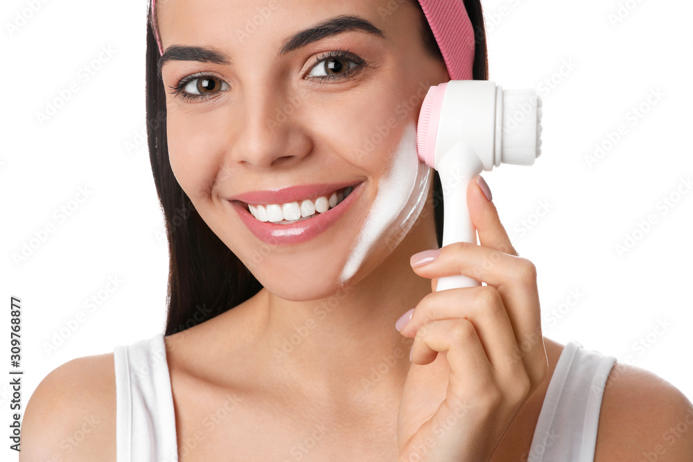 Young woman using facial cleansing brush on white background, closeup. Washing accessory Young woman using facial cleansing brush on white background, closeup. Washing accessory
