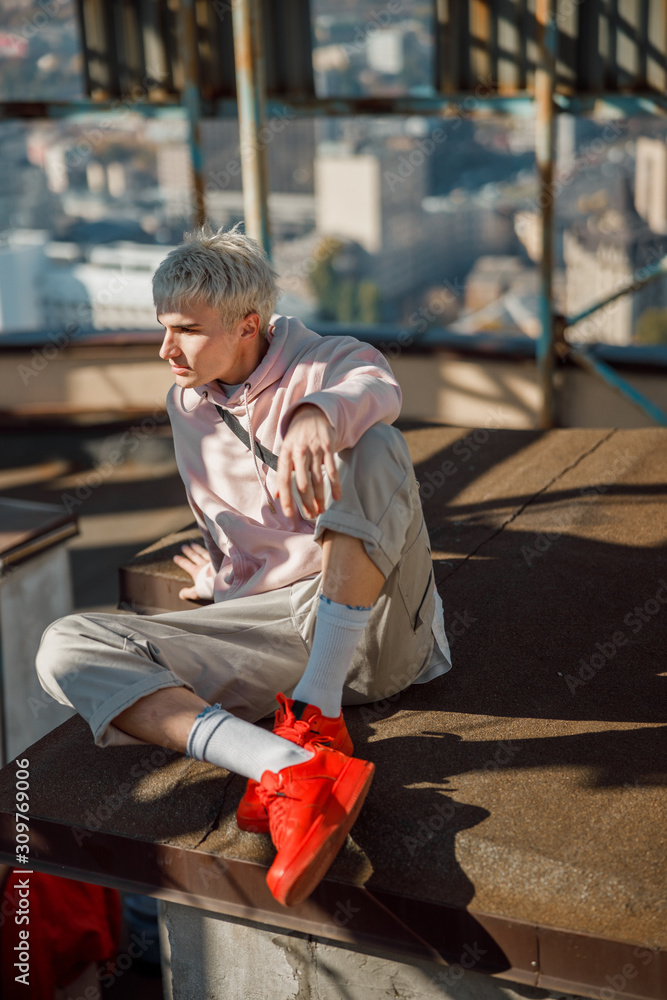 Obraz premium Young guy in red sneakers looking away on roof