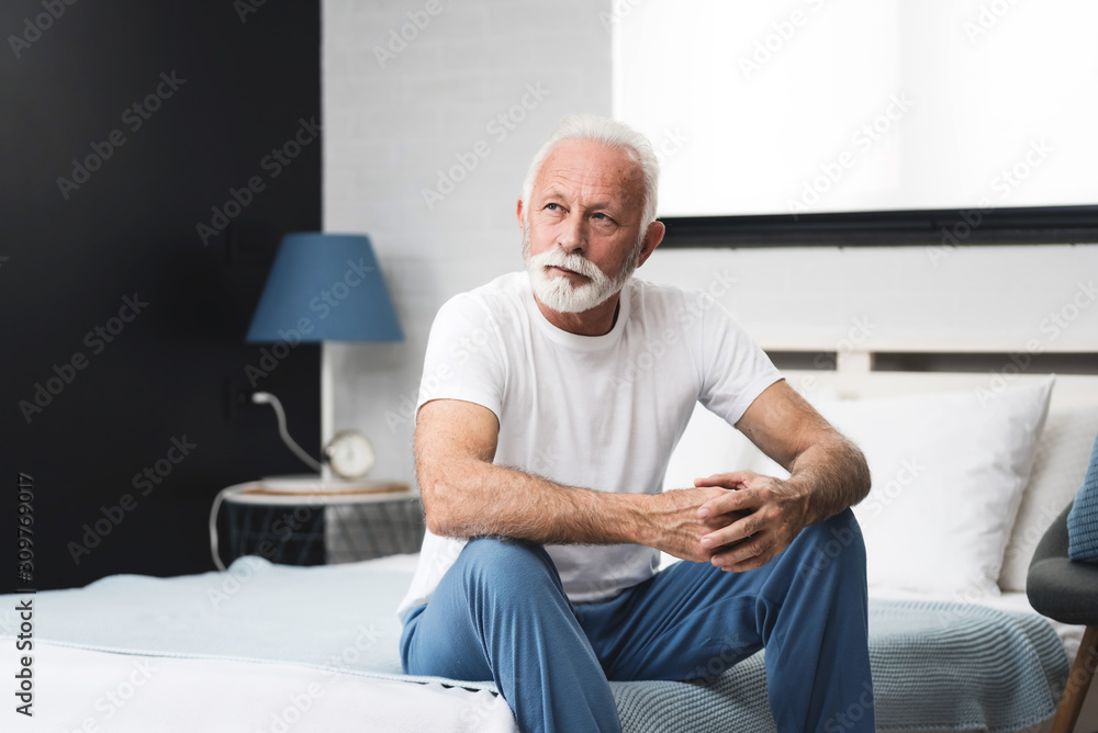 Senior man sitting on bed in morning