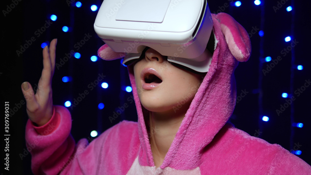girl in pink pajamas kigurumi in VR glasses on a black background ...