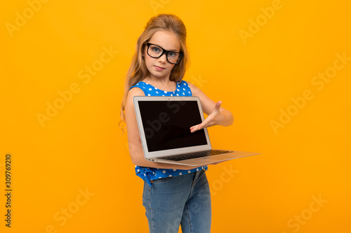 caucasian girl holds laptop screen with mockup forward on an orange background