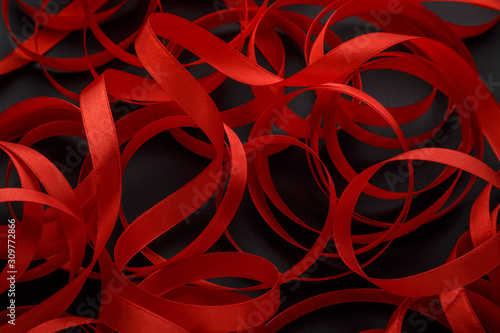 Red scarlet silk holiday ribbon on a black background. Valentine's Day. Christmas. Romantic background.