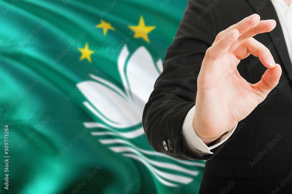 Fototapeta premium Macao acceptance concept. Elegant businessman is showing ok sign with hand on national flag background.