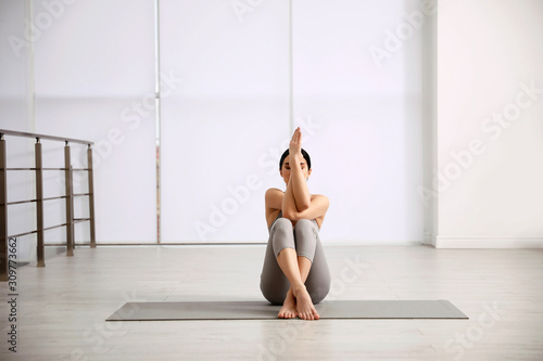 Young woman practicing eagle asana in yoga studio. Garudasana pose