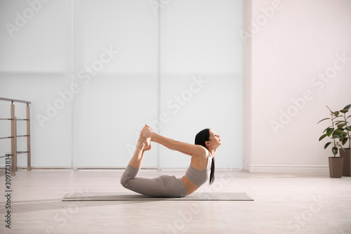 Young woman practicing bow asana in yoga studio. Dhanurasana pose