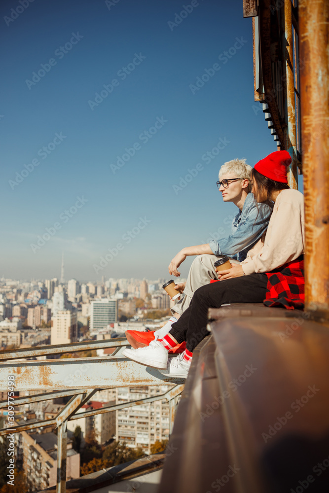 Obraz premium Lovely couple sitting on the edge of the roof
