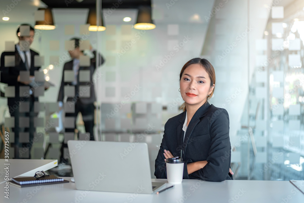 Portrait of young asian businesswoman sitting at her office looking at camera. background of businessman. Portrait of young asian businesswoman sitting at her office looking at camera. background of businessman.