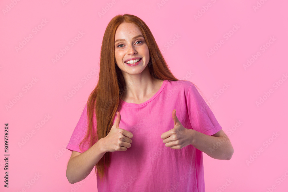 beautiful young woman with red hair on a pink background with hand gesture beautiful young woman with red hair on a pink background with hand gesture