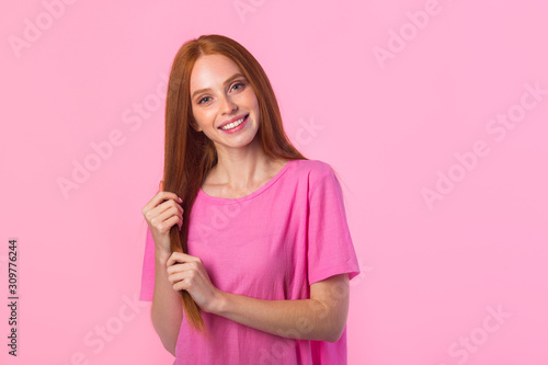 beautiful young woman with red hair on a pink background © Alexandr