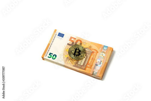 Crypto currency concept - a bitcoin with euro bills isolated on white. Bitcoin and Euro banknotes. Cryptocurrency lies on the money. Golden bitcoin on fifty euro banknotes.