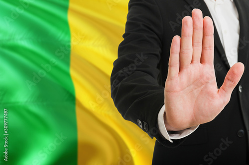 Mali rejection concept. Elegant businessman is showing stop sign with hand on national flag background.
