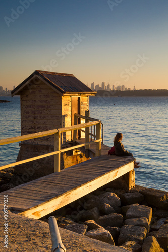 Girl watching sunset at a beach shed