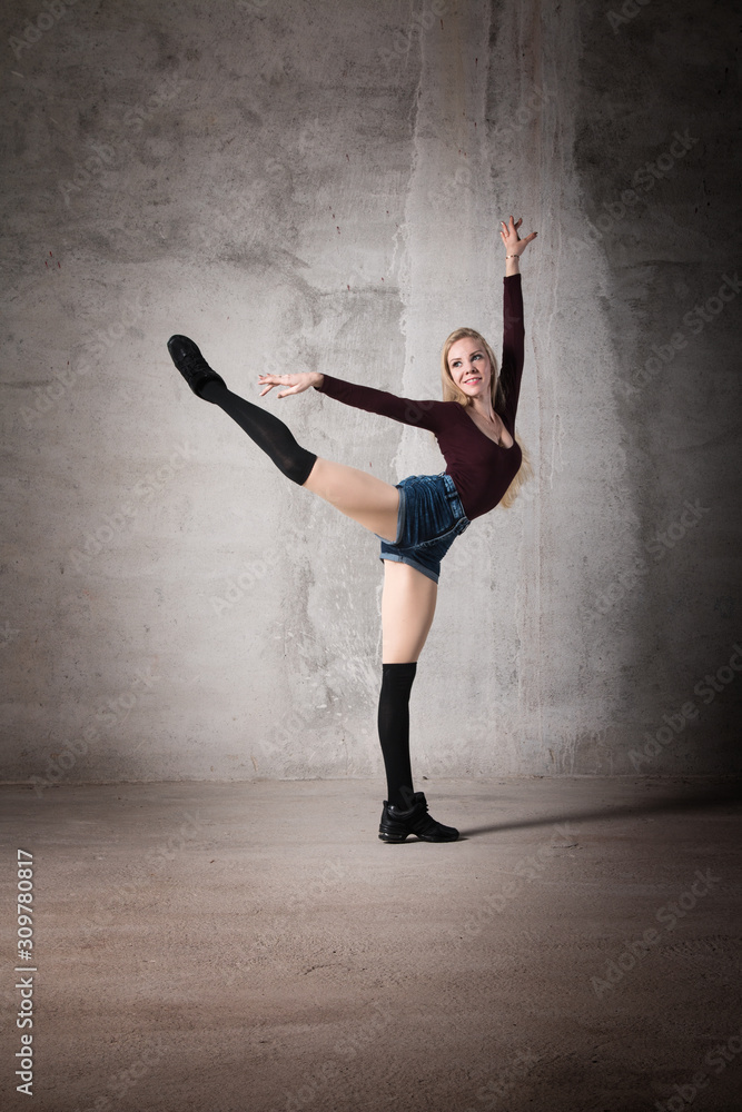 Female dancer in a ballet pose on a gray background. Dance and movement, active, athletic figure, body, active life