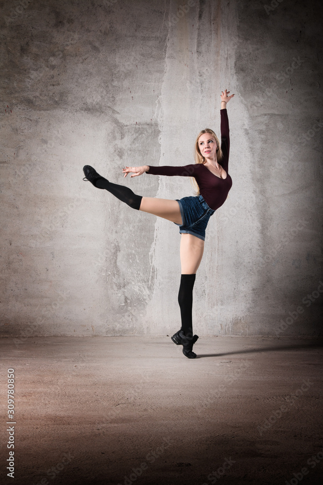 Female dancer in a ballet pose on a gray background. Dance and movement, active, athletic figure, body, active life