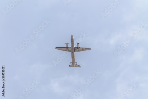 Underside view of a commercial airliner flying, blue sky as background