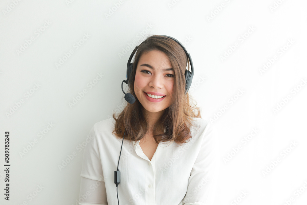 Asian woman on white shirt speak with headphone and using laptop on white background smile and happy face operator concept Asian woman on white shirt speak with headphone and using laptop on white background smile and happy face operator concept