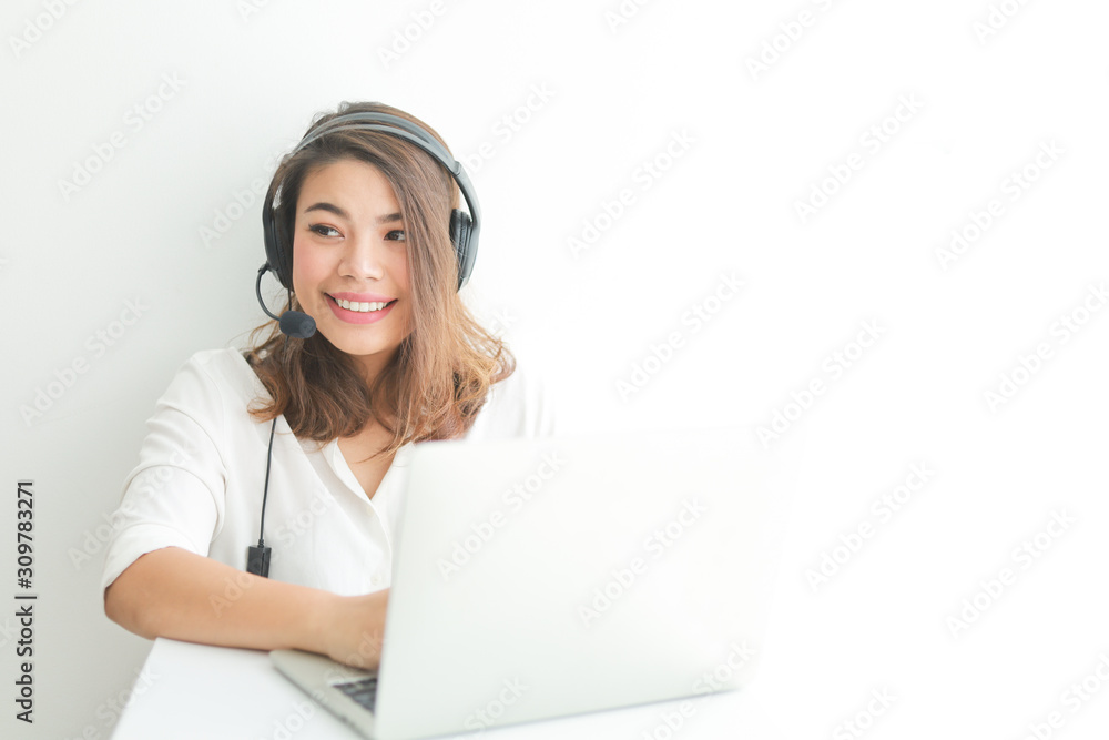 Asian woman on white shirt speak with headphone and using laptop on white background smile and happy face operator concept Asian woman on white shirt speak with headphone and using laptop on white background smile and happy face operator concept