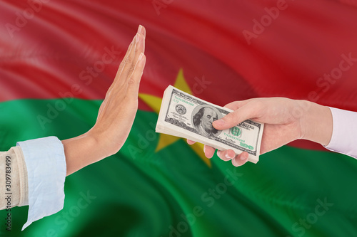 Burkina Faso bribery refusing. Closeup of female hands extending a pile of dollar bills to the male hands gesturing as if rejecting the money.
