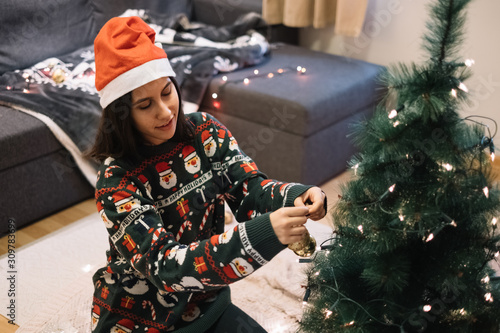 Woman decorating a Christmas tree with balls