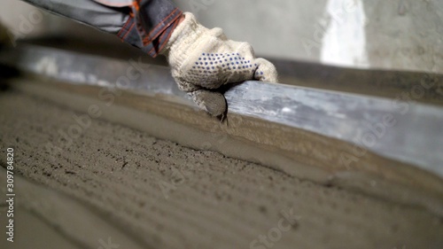 Leveling the floor of a large construction spatula. The worker pours the floors with mortar. The builder is working on pouring the house floor with cement mortar.