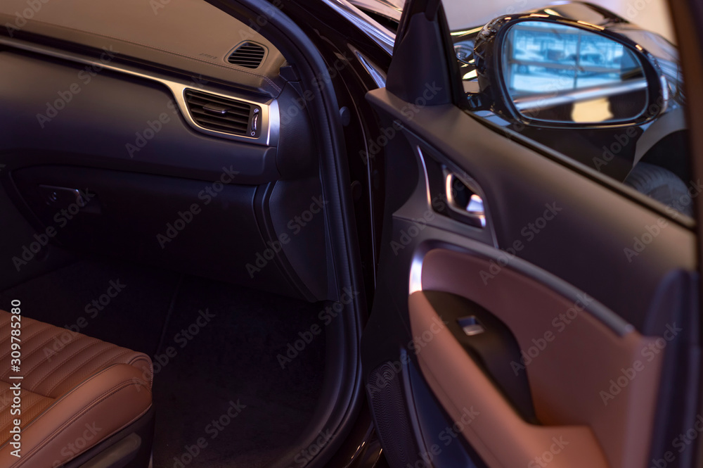 Open door and  interior of  car. Natural brown premium leather trim. Side view.