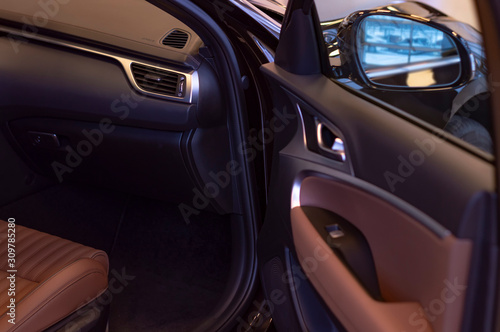 Open door and interior of car. Natural brown premium leather trim. Side view.