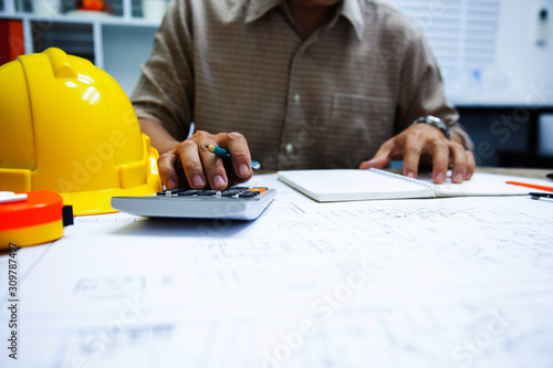 Architect calculating structure estimates in blueprint at Construction Site With drawing equipment.concept