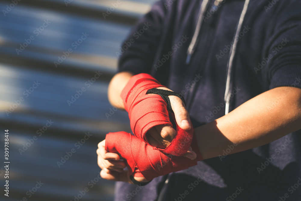 Close up view of young male hands with boxing bands. Boy prepares for a boxe workout by wrapping his hand. Boxer ready to throw punches. Teenager Sport, youth, determination and training gym concept.