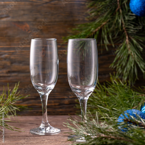 Glasses for champagne and a bottle on the background of New Year's decor. Copy space. Close-up.