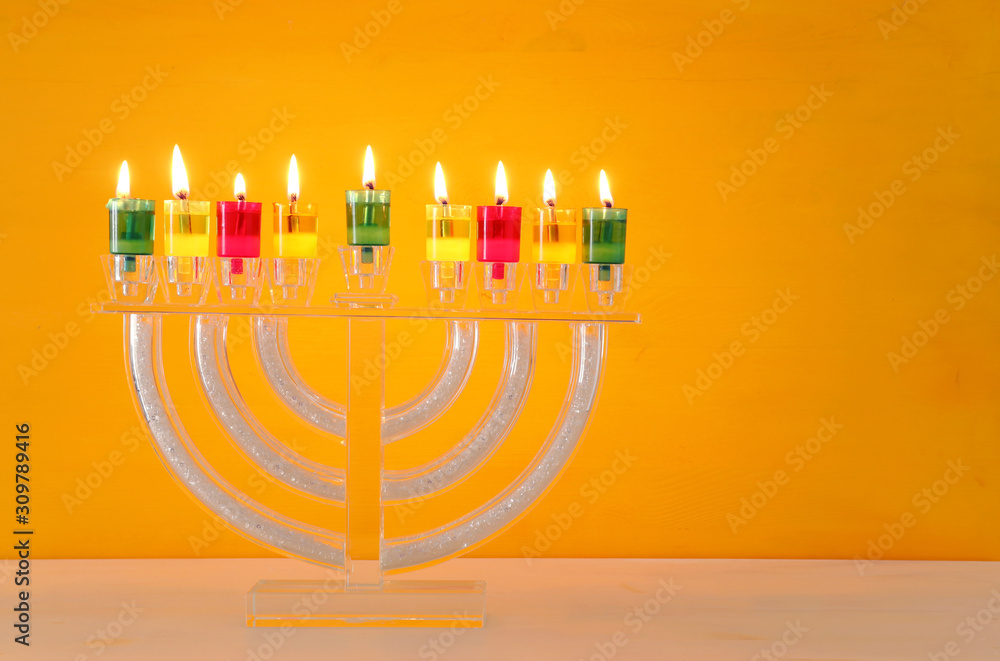 image of jewish holiday Hanukkah background with crystal menorah (traditional candelabra) and colorful oil candles image of jewish holiday Hanukkah background with crystal menorah (traditional candelabra) and colorful oil candles
