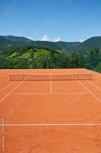 Empty outdoor tennis court in a picturesque landscape on a sunny day