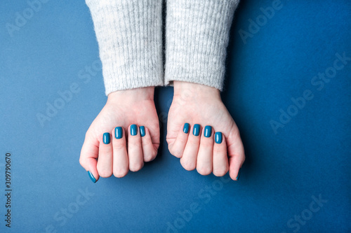 Stylish female manicure. Beautiful female hands on blue background. Color concept