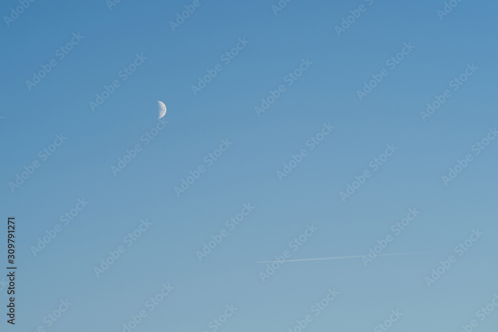 Airplane in blue sky faraway with moon on background Airplane in blue sky faraway with moon on background