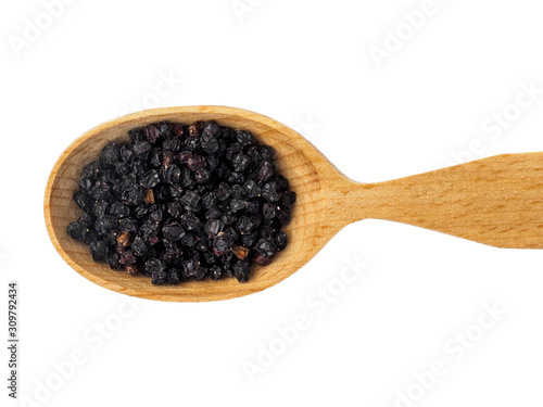 Dried Sambucus berries or elderberries in a wooden spoon on a white background