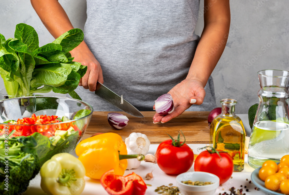 Woman cuts onions and makes salad in the kitchen. Healthy diet concept. Woman cuts onions and makes salad in the kitchen. Healthy diet concept.