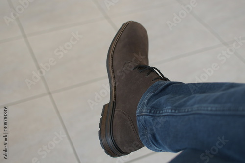 leg with brown shoe and classic blue jeans color of the year pantone on white floor