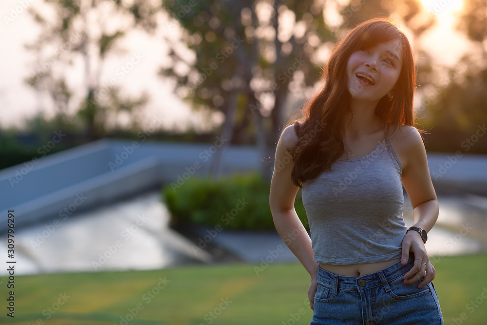 portrait of beautiful asian woman laughing in park over sunset background. Free from copy space. Freedom and lifestyle concept. portrait of beautiful asian woman laughing in park over sunset background. Free from copy space. Freedom and lifestyle concept.