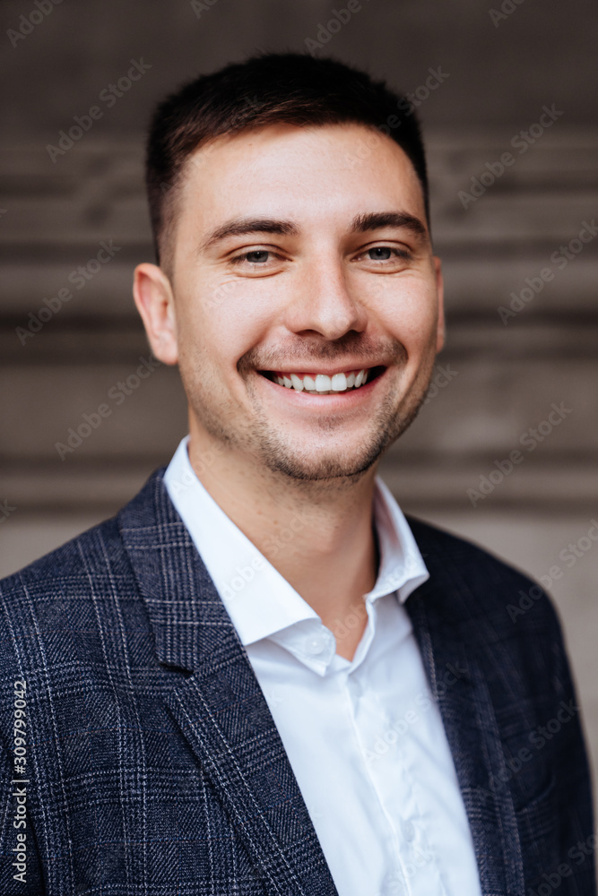 Elegant smiling handsome groom in blue suit posing on the background of old castle Elegant smiling handsome groom in blue suit posing on the background of old castle