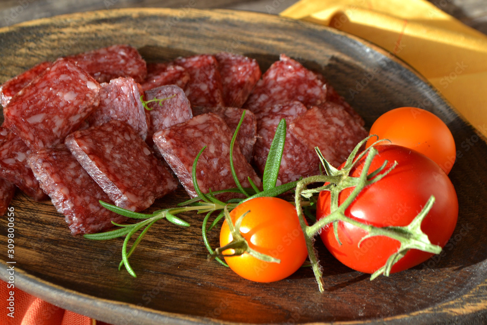 Dry sausage and Italian salami on raw wooden cutting board close up Dry sausage and Italian salami on raw wooden cutting board close up