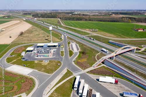 View from the top of the highway, adjacent gas station and truck stop. There is a pedestrian bridge over the motorway. Around-forests and fields.