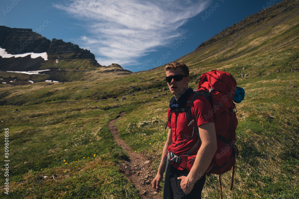hiker with backpack hiking hornstrandir nature reserve track in westfjords iceland